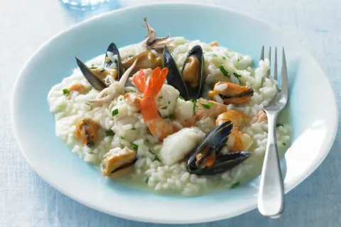 Un cremoso risotto alla pescatora, ricco di gamberi, cozze e calamari, pronto per essere gustato.