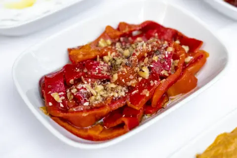 Peperoni al microonde, dolci e succosi, conditi con aglio tritato e spezie, serviti in una ciotola bianca.