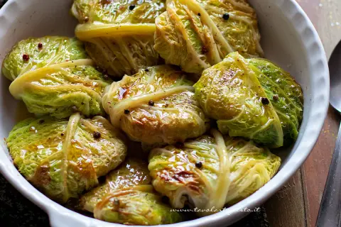 Involtini di verza succulenti, conditi con pepe nero e spezie, in una ciotola bianca.