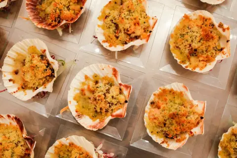 Deliziose capesante gratinate, servite in conchiglie, pronte per essere gustate.