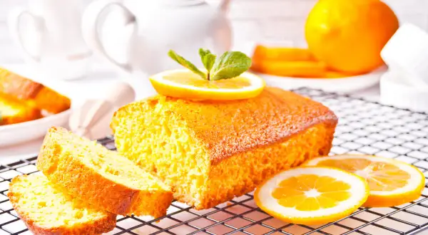 Un delizioso plumcake al limone, decorato con fette d'arancia e menta, pronto per essere gustato.