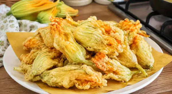 Fiori di zucca fritti, croccanti e dorati, preparati con una leggera pastella per fiori di zucca.