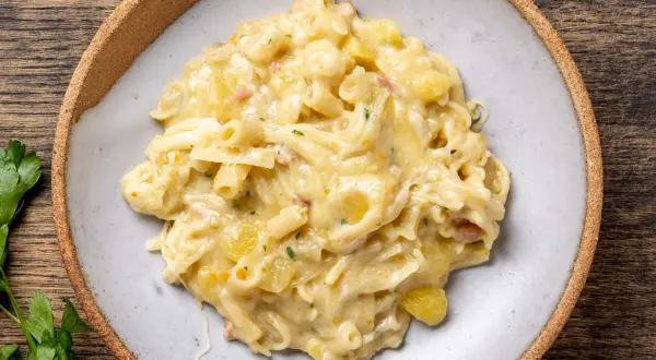 Un piatto invitante di pasta con patate cremosa, arricchita da pezzetti di pancetta e prezzemolo fresco.