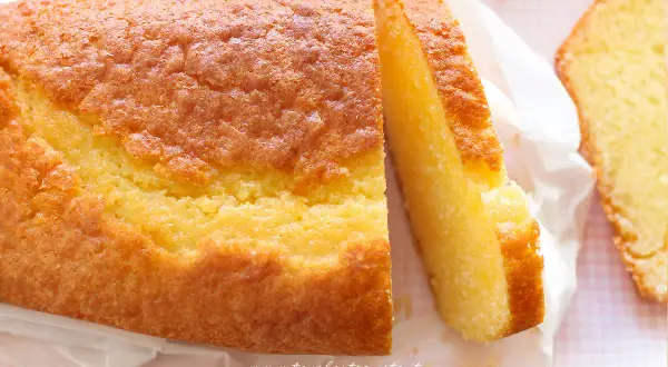 Un soffice plumcake allo yogurt, dorato e invitante, con una fetta tagliata che ne mostra la morbidezza. Perfetto per la colazione.