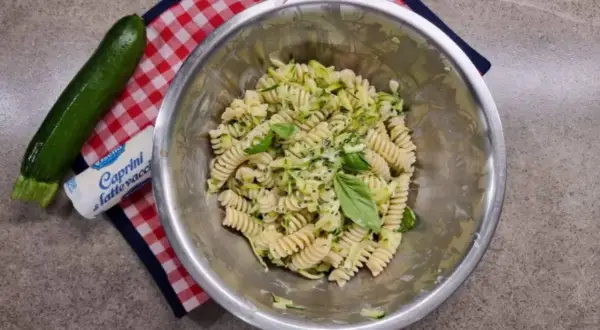 Pasta fredda con zucchine, basilico e formaggio fresco. Un piatto estivo leggero e gustoso, pronto per essere servito.