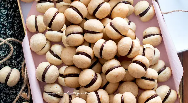 Una teglia piena di deliziosi baci di dama, biscotti friabili con un cuore di cioccolato fondente.