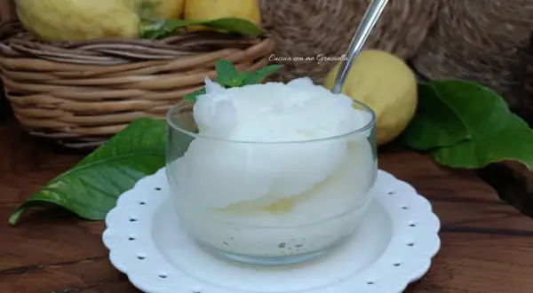 Una coppa di granita al limone, fresca e dissetante, con limoni freschi sullo sfondo.