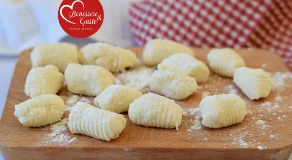 Gnocchi di ricotta freschi, pronti per essere cucinati, su un tagliere di legno.