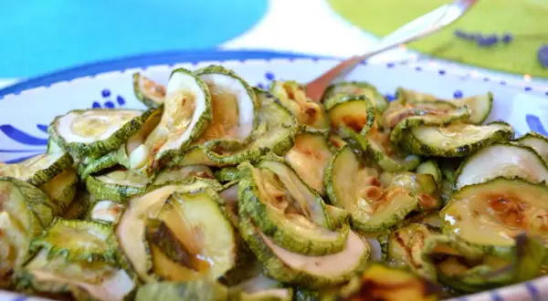 Fette di zucchine in carpione, condite con olio e aceto, pronte per essere gustate.