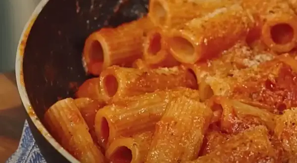 Rigatoni conditi con un sugo rosso ricco e cremoso, pronti per essere gustati in una **pasta alla zozzona** da leccarsi i baffi.