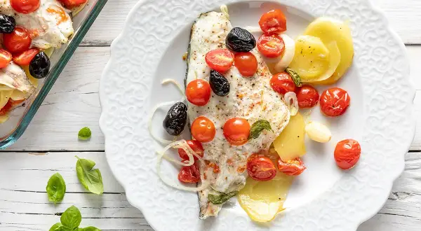 Filetti di orata al forno con pomodorini, olive nere e patate. Un piatto saporito e colorato, pronto per essere gustato.