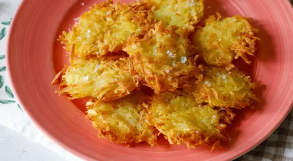 Tortel di patate dorati e croccanti, cosparsi di sale grosso, su un piatto rosa.