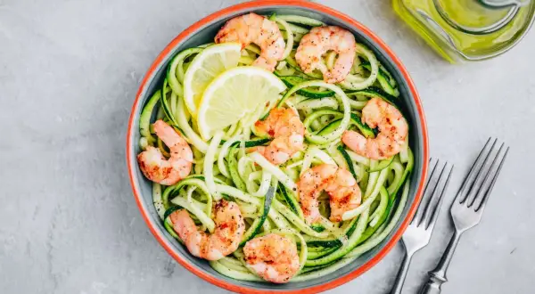 Spaghetti di zucchine con gamberi succulenti e spicchi di limone, un piatto leggero e gustoso.