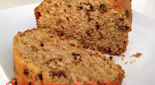 Plumcake con gocce di cioccolato, soffice e invitante, tagliato a fette su un piatto bianco.