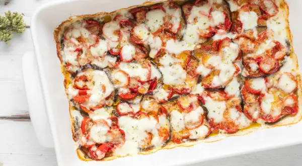 Melanzane al forno, un piatto invitante con fette di melanzane, pomodori e mozzarella filante, pronto per essere gustato.