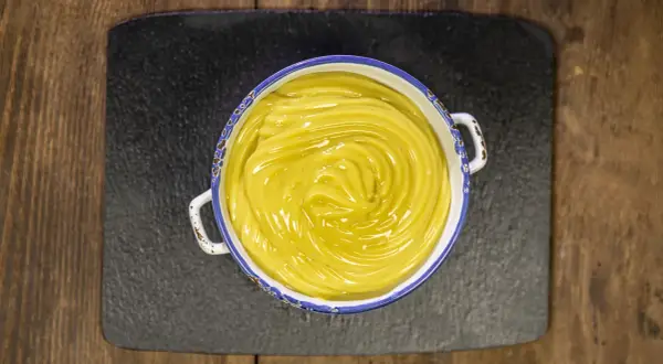 Una ciotola di cremosa crema pasticcera vegana, con un vortice lucido al centro, pronta per essere gustata.