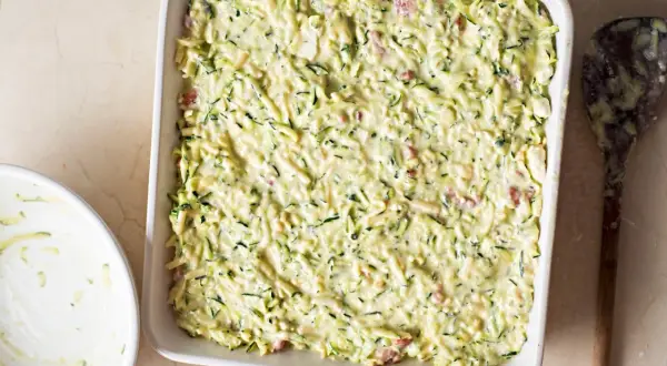 Sformato di zucchine pronto per essere infornato, con zucchine grattugiate e un cremoso impasto.