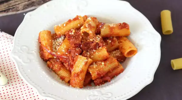 Piatto di rigatoni conditi con un sugo rosso piccante alla nduja, spolverati di parmigiano.