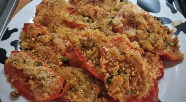 Pomodori al forno ripieni di pangrattato e erbe aromatiche, dorati e invitanti.