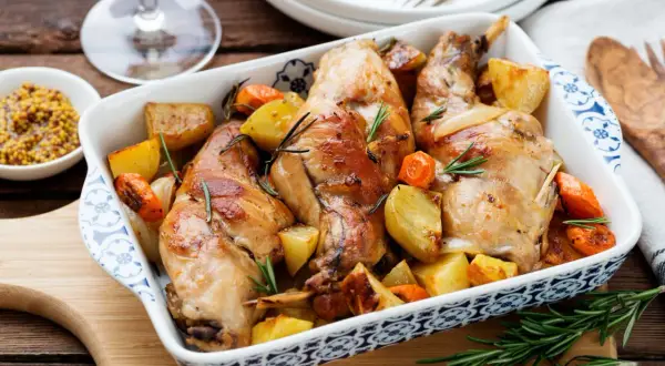 Delizioso coniglio al forno con patate e carote, profumato al rosmarino. Un piatto rustico e saporito, pronto per essere gustato.