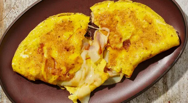 Omelette dorata e soffice, ripiena di formaggio filante. Una deliziosa omelette ricetta per una colazione o un pasto veloce.