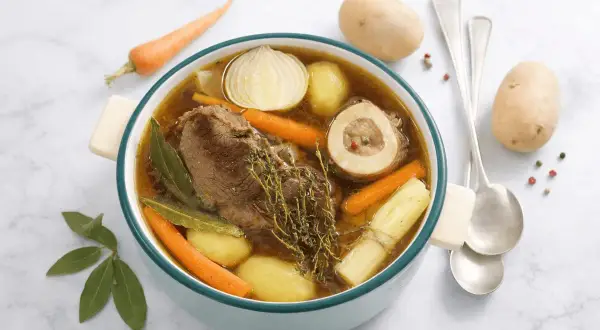 Un ricco brodo di carne con ossobuco, patate, carote, cipolla e erbe aromatiche. Un piatto confortante e saporito.
