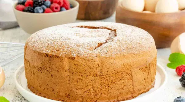 Una soffice torta margherita spolverata di zucchero a velo, pronta per essere gustata con frutti di bosco freschi.
