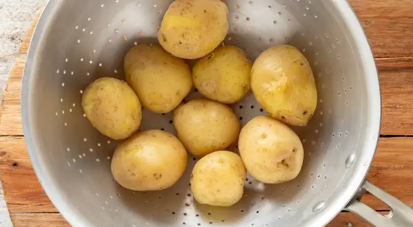 Patate bollite appena scolate in un colino, pronte per essere condite.