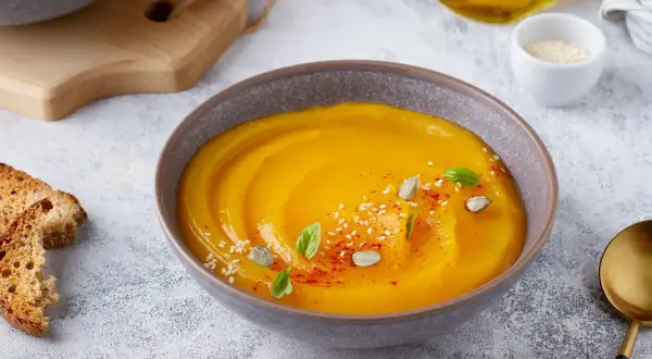 Vellutata di zucca cremosa, guarnita con semi di zucca, sesamo, paprika e basilico. Servita con crostini dorati.