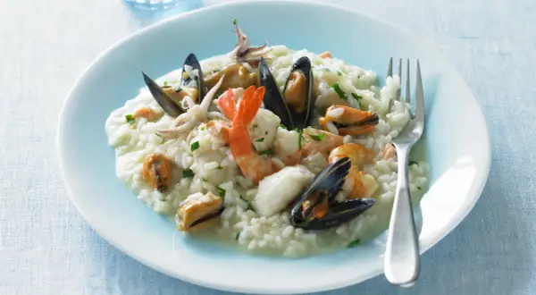 Un cremoso risotto alla pescatora, ricco di gamberi, cozze e calamari, pronto per essere gustato.