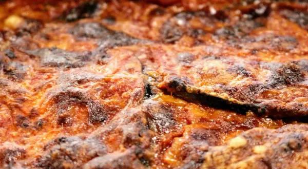 Parmigiana di melanzane non fritte, dorata e invitante, con strati di melanzane, pomodoro e formaggio filante. Una delizia leggera e gustosa.
