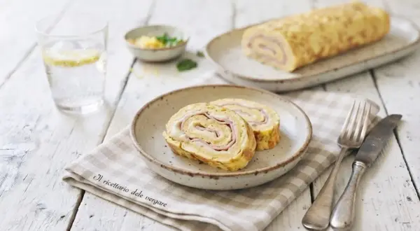 Delizioso rotolo di frittata con prosciutto e formaggio, servito su un piatto con una forchetta e un coltello.