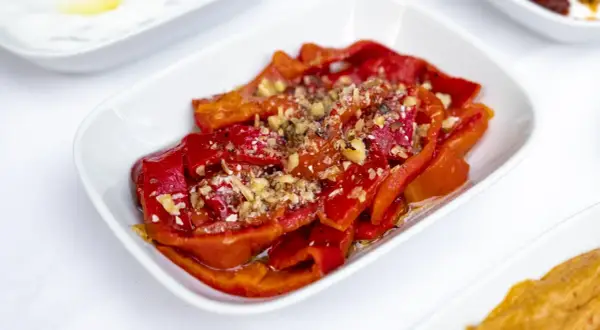Peperoni al microonde, dolci e succosi, conditi con aglio tritato e spezie, serviti in una ciotola bianca.