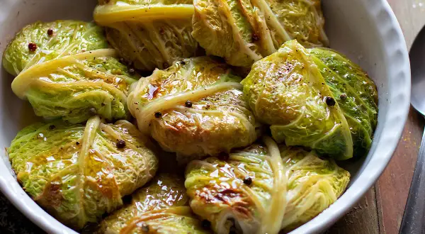 Involtini di verza succulenti, conditi con pepe nero e spezie, in una ciotola bianca.