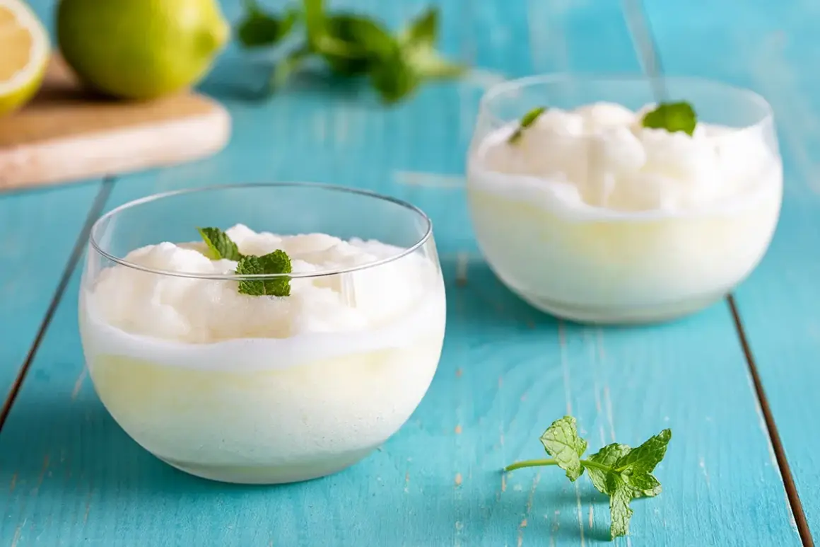 Due bicchieri di sorbetto al limone veloce, guarniti con menta fresca, su un tavolo di legno blu.