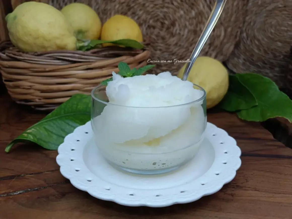 Una coppa di granita al limone, fresca e dissetante, con limoni freschi sullo sfondo.