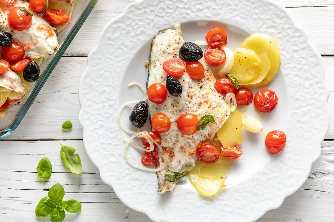 Filetti di orata al forno con pomodorini, olive nere e patate. Un piatto saporito e colorato, pronto per essere gustato.