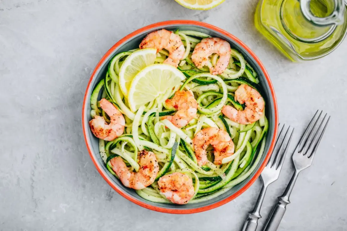 Spaghetti di zucchine con gamberi succulenti e spicchi di limone, un piatto leggero e gustoso.
