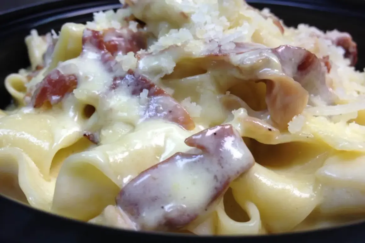 Primo piatto cremoso di pasta panna e speck, cosparso di formaggio grattugiato.