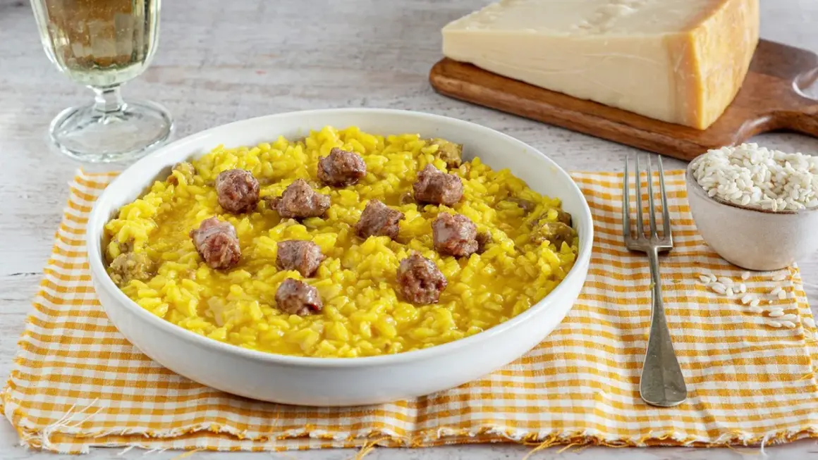Un invitante risotto alla monzese, giallo intenso e arricchito da pezzetti di salsiccia, pronto per essere gustato.