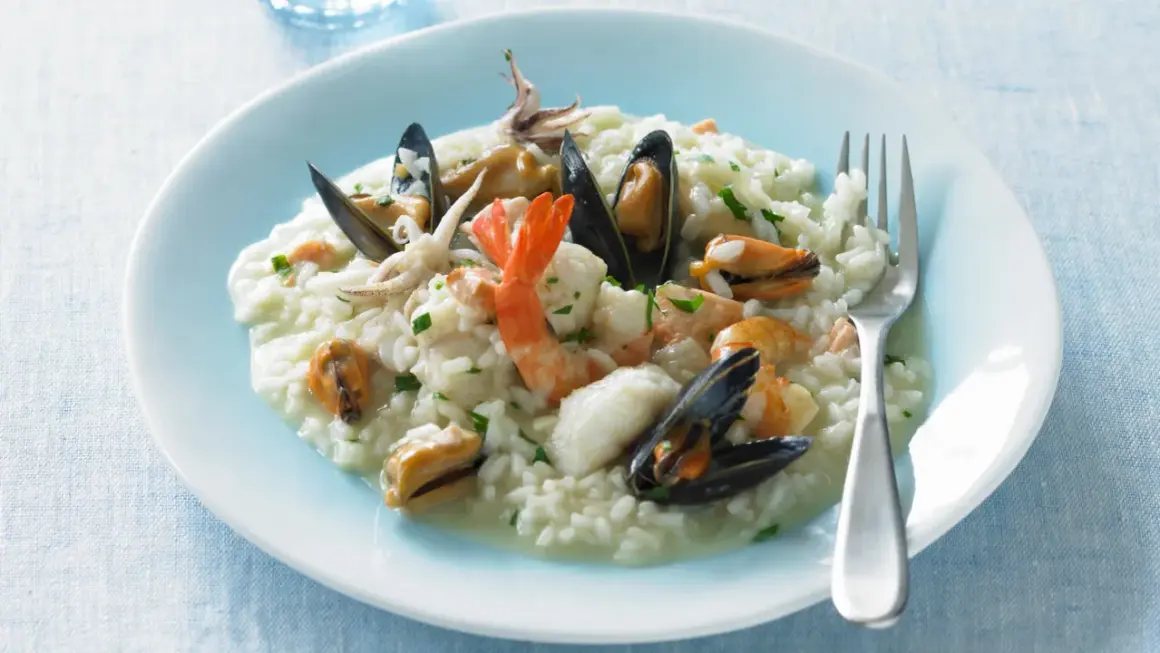 Un cremoso risotto alla pescatora, ricco di gamberi, cozze e calamari, pronto per essere gustato.