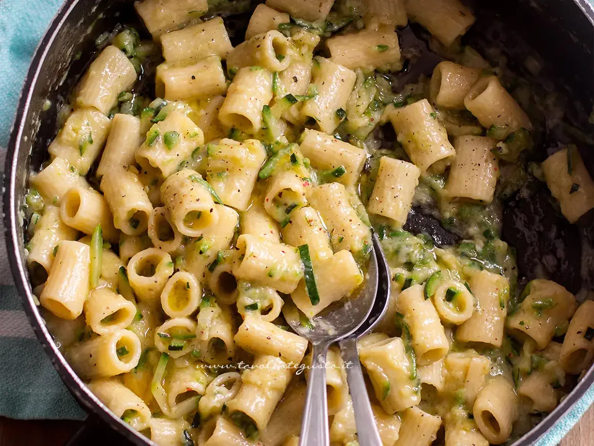 Close-up of rigatoni pasta with zucchini in a creamy sauce in a pot.