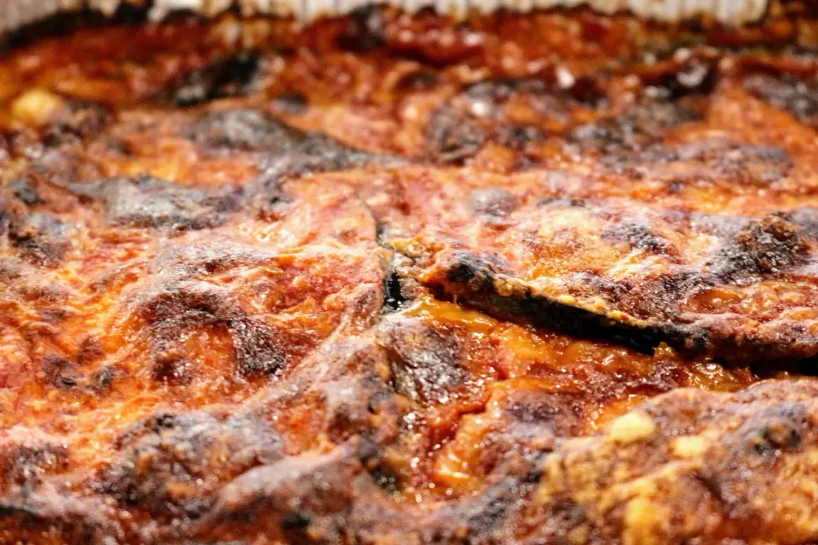 Parmigiana di melanzane non fritte, dorata e invitante, con strati di melanzane, pomodoro e formaggio filante. Una delizia leggera e gustosa.