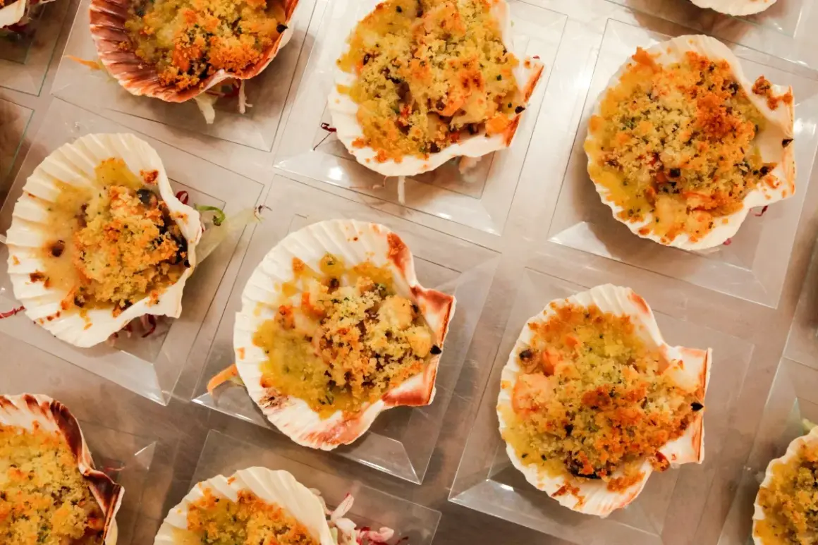 Deliziose capesante gratinate, servite in conchiglie, pronte per essere gustate.