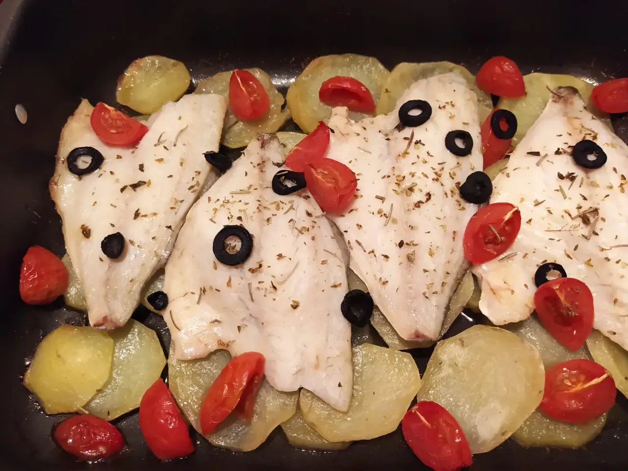 Filetti di orata al forno con patate, pomodorini e olive nere, un piatto semplice e gustoso.