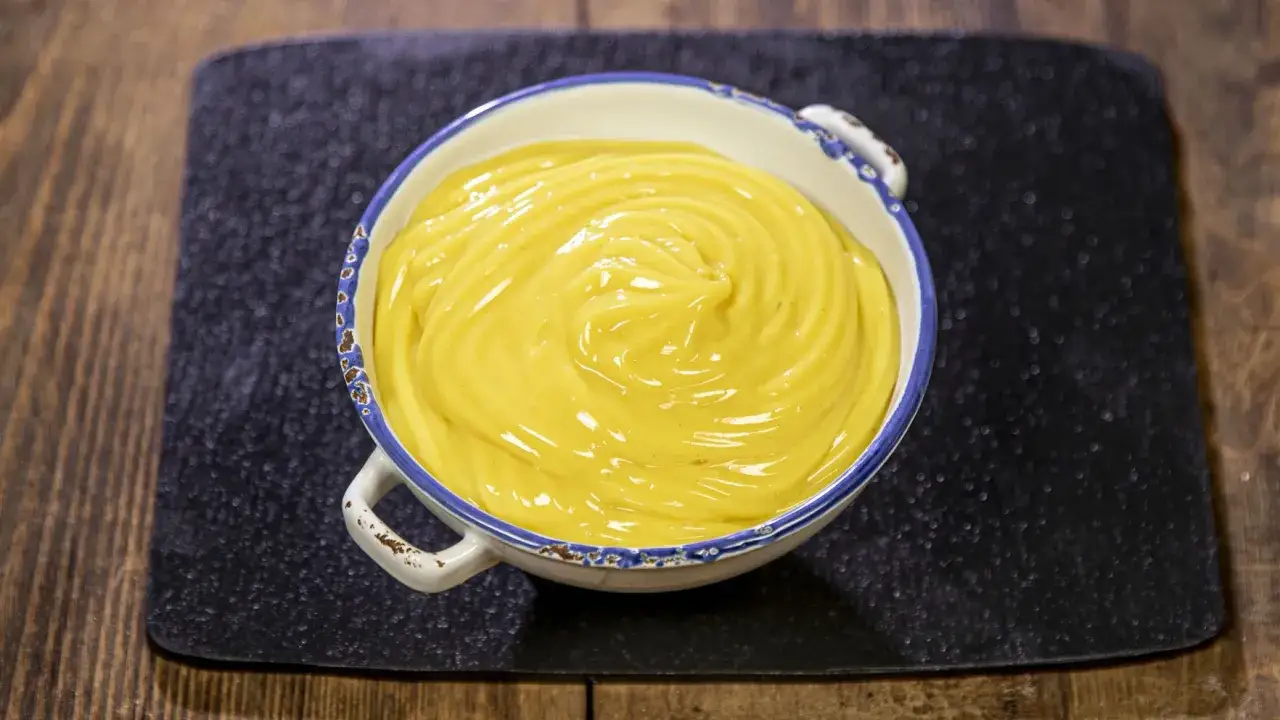 Una ciotola di cremosa crema pasticcera vegana, con un vortice invitante, pronta per essere gustata.