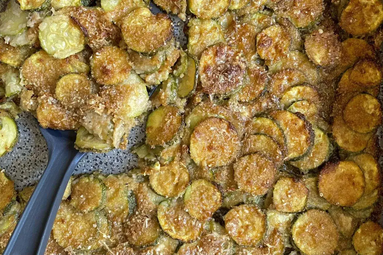 Fette di zucchine al forno dorate e croccanti, cosparse di parmigiano. Un contorno saporito e facile da preparare.