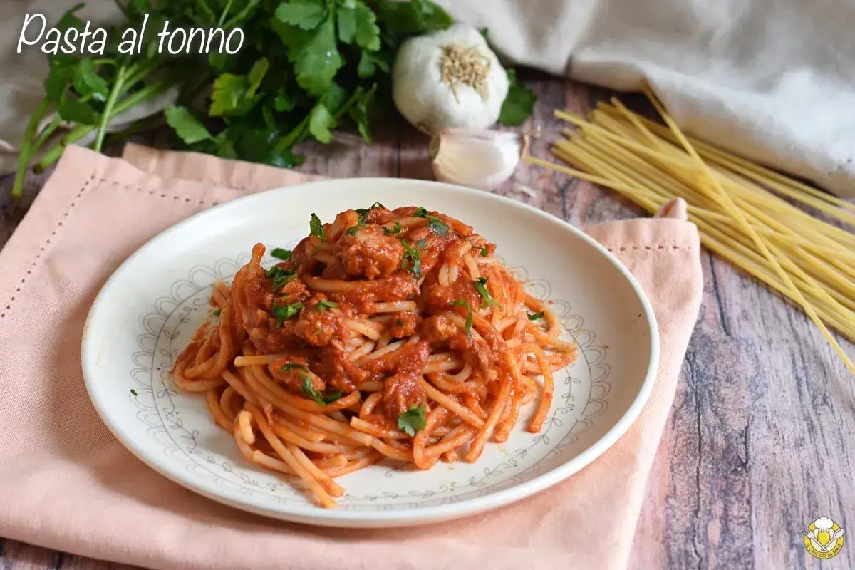 Un piatto di pasta al tonno fumante, condita con un sugo rosso e prezzemolo fresco, pronta per essere gustata.