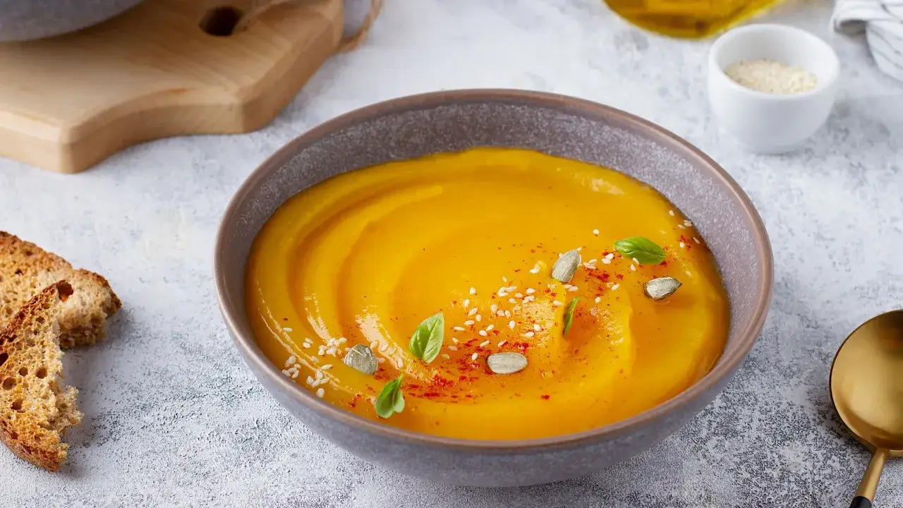 Vellutata di zucca cremosa, guarnita con semi di zucca, sesamo e paprika. Servita con crostini dorati.
