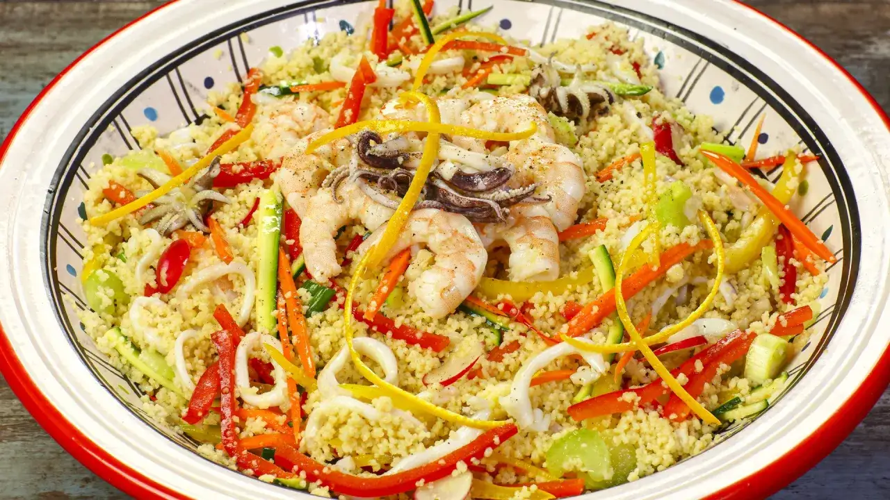 Un saporito cous cous con gamberi, calamari e verdure colorate, un piatto estivo perfetto.